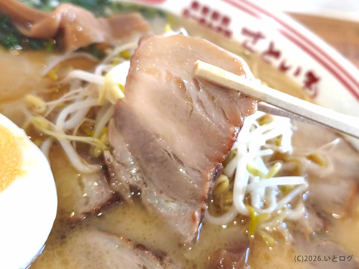らーめん本舗 さといも 本店のラーメンにトッピングされた豚チャーシューを箸で持ち上げた様子