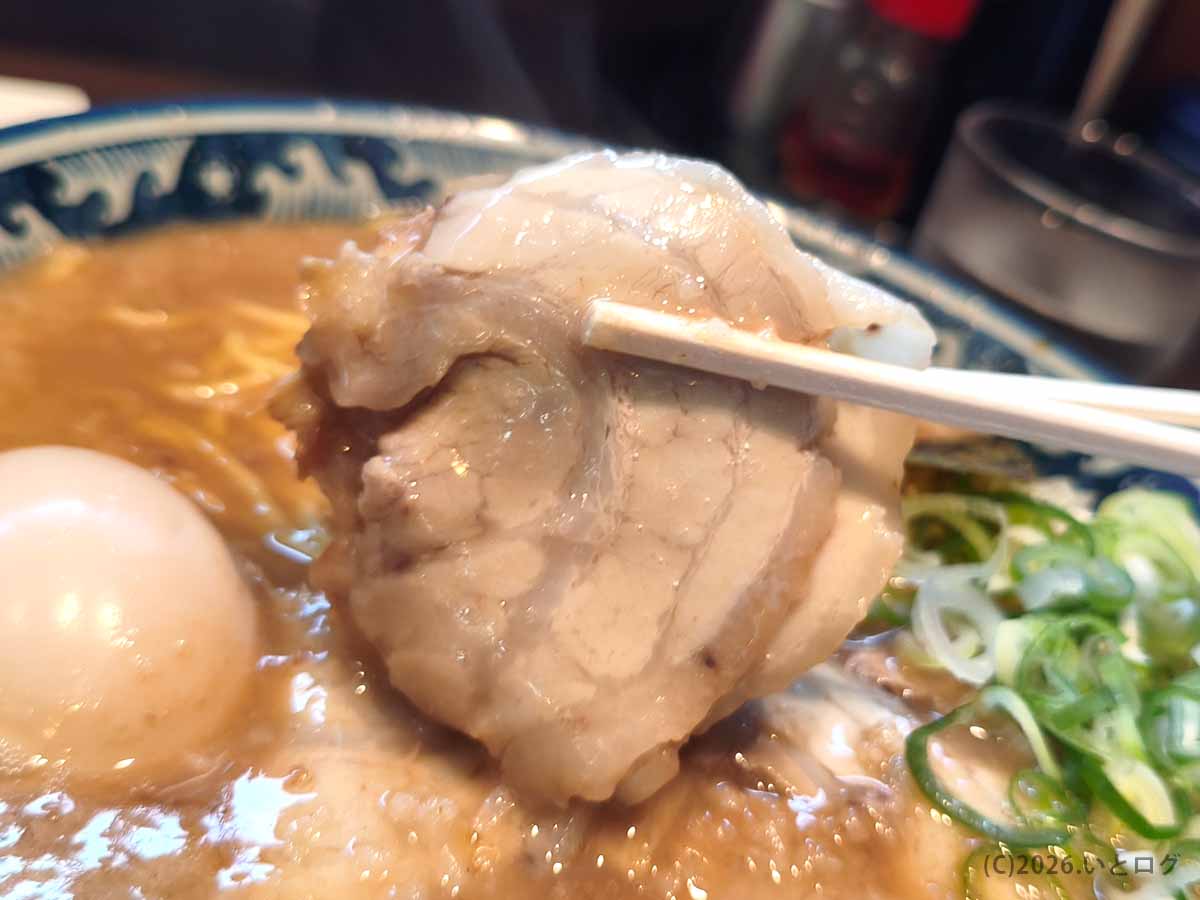風来軒 加納本店のとんこつラーメンにのったチャーシュー。脂身をまとったやわらかな豚肉を箸で持ち上げた様子