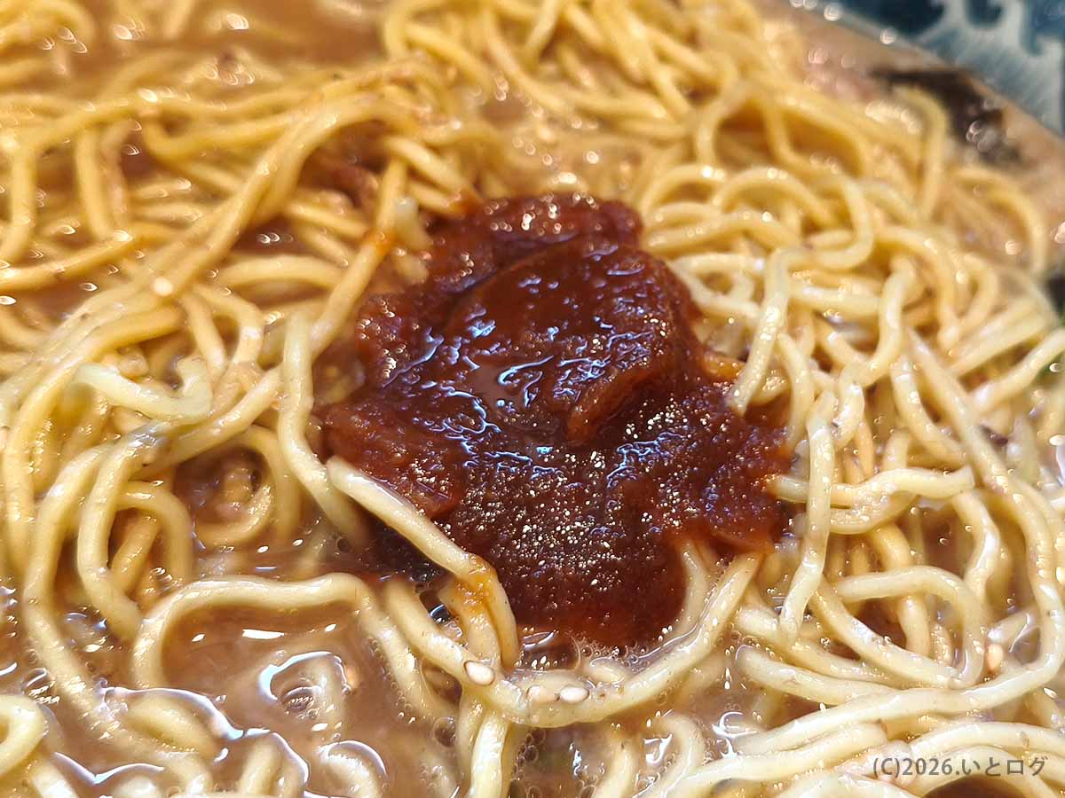 風来軒 加納本店のとんこつラーメンに辛味噌を加えて味変。濃厚豚骨スープの中央に赤い辛味噌をのせた様子