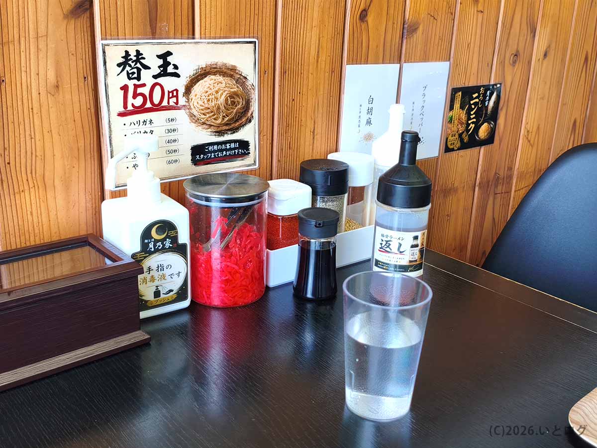 月乃家のテーブルに用意された紅生姜やラーメンの返し、おろしニンニクなどの卓上調味料。自分好みの味にアレンジしてラーメンを楽しめる環境。