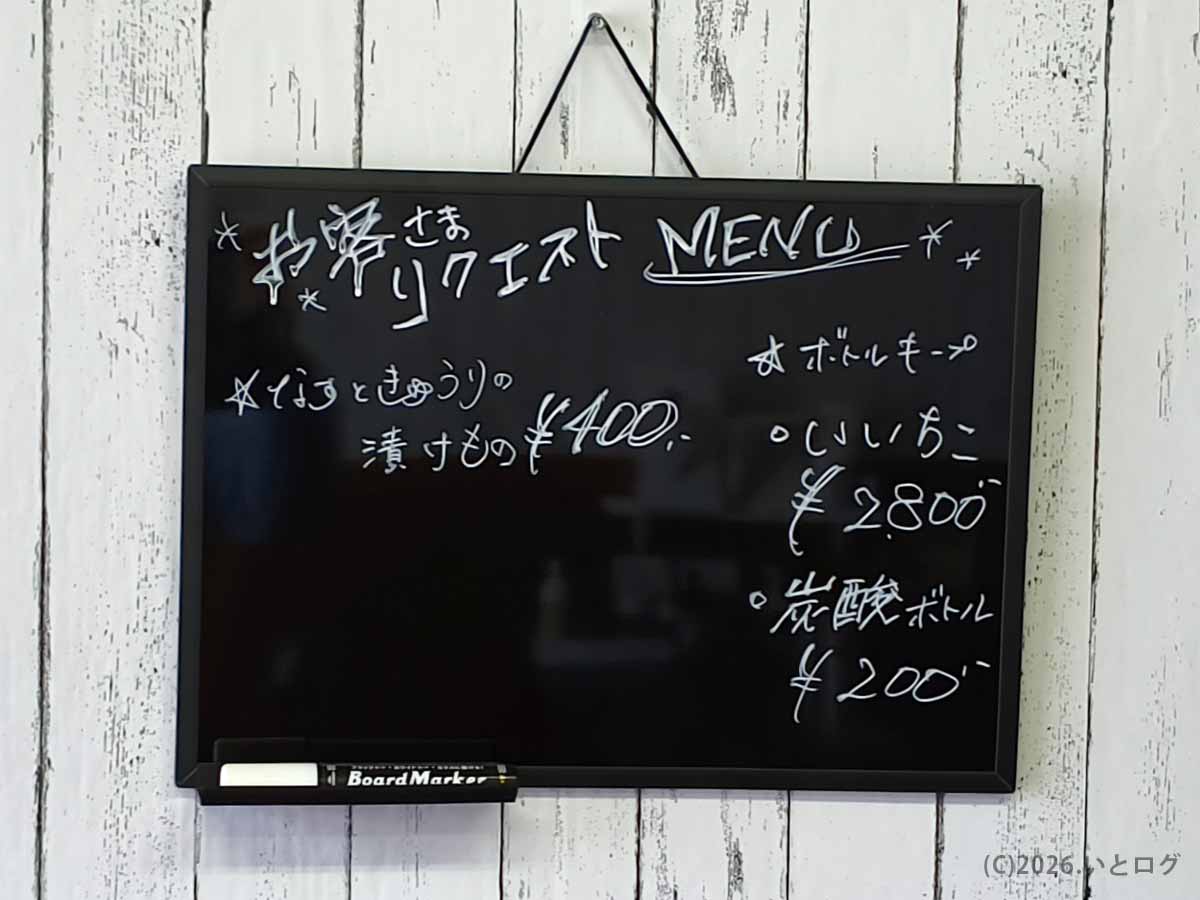 店内の黒板に書かれた「お客様リクエストMENU」。「なすときゅうりの漬けもの」やボトルキープの案内など、アットホームな居酒屋らしさが伝わる壁掛け黒板。