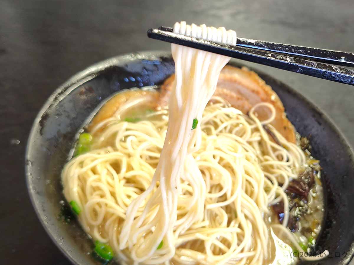 麺と酒 月乃家のラーメン。箸でリフトアップされた、スープがよく絡むきれいなストレート細麺のクローズアップ。