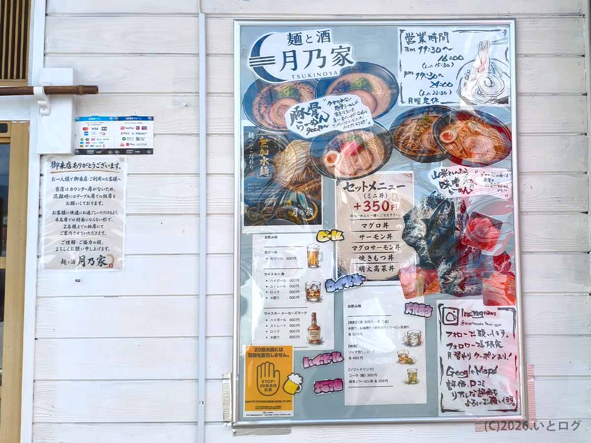 店舗の外壁に掲示された、麺と酒 月乃家の営業時間やメニュー、Instagramアカウント、Google Mapsのクチコミ案内が書かれた大型の看板。