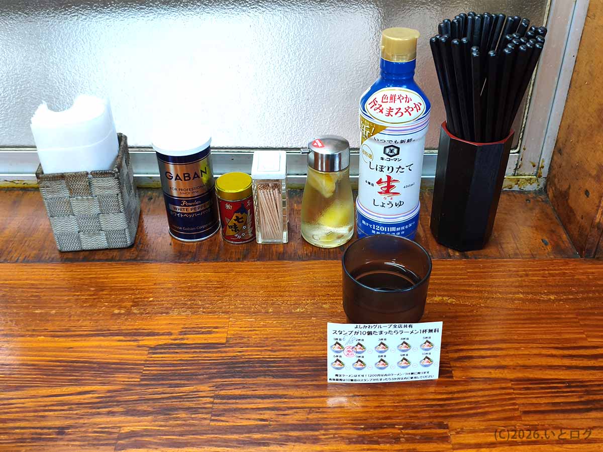 中華そば よしかわ 上尾店の卓上に並ぶ生しょうゆや白こしょう、七味などの調味料