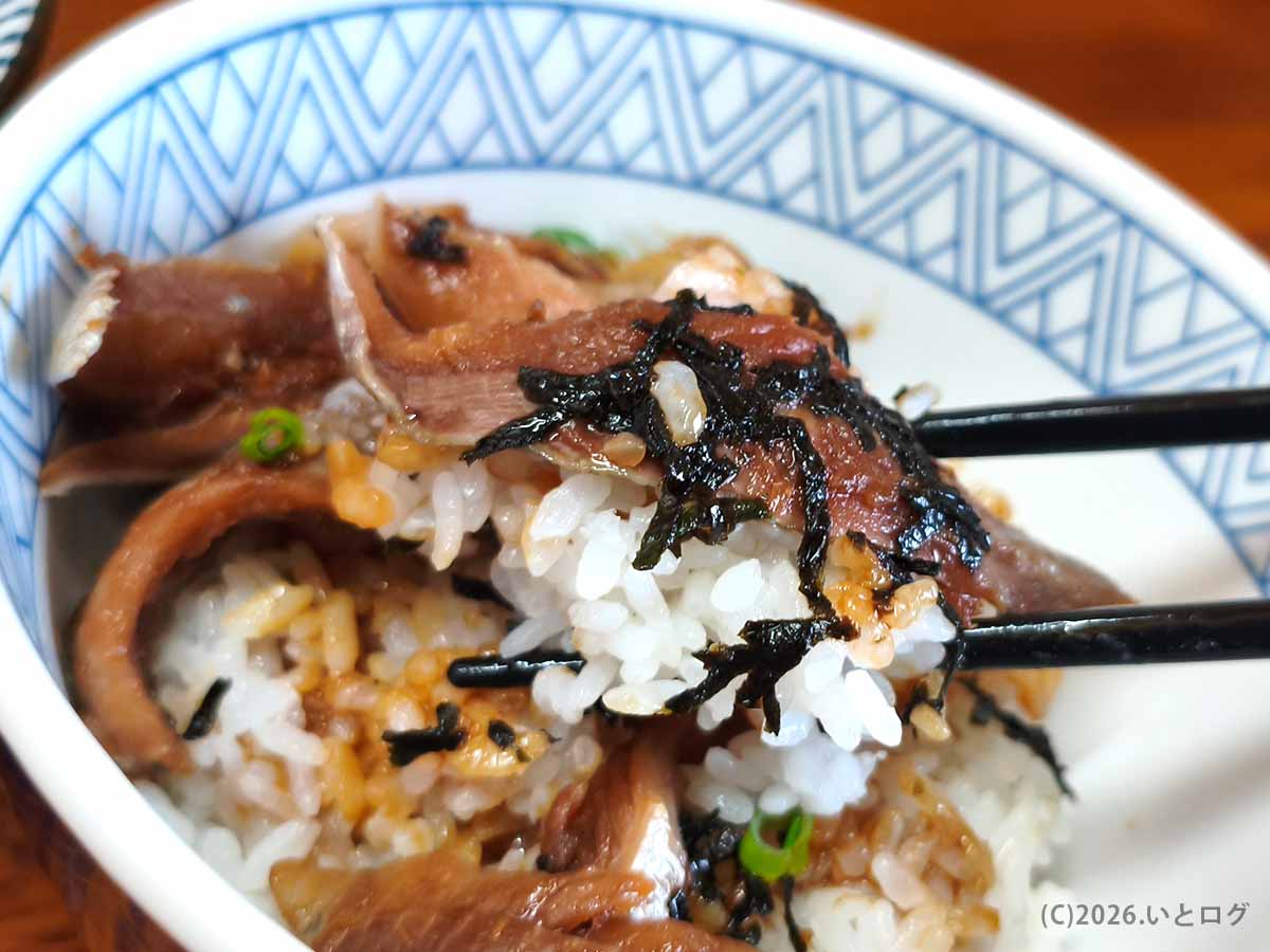 中華そば よしかわ 上尾店のいわし丼を海苔とタレを絡めたご飯と一緒に食べる様子