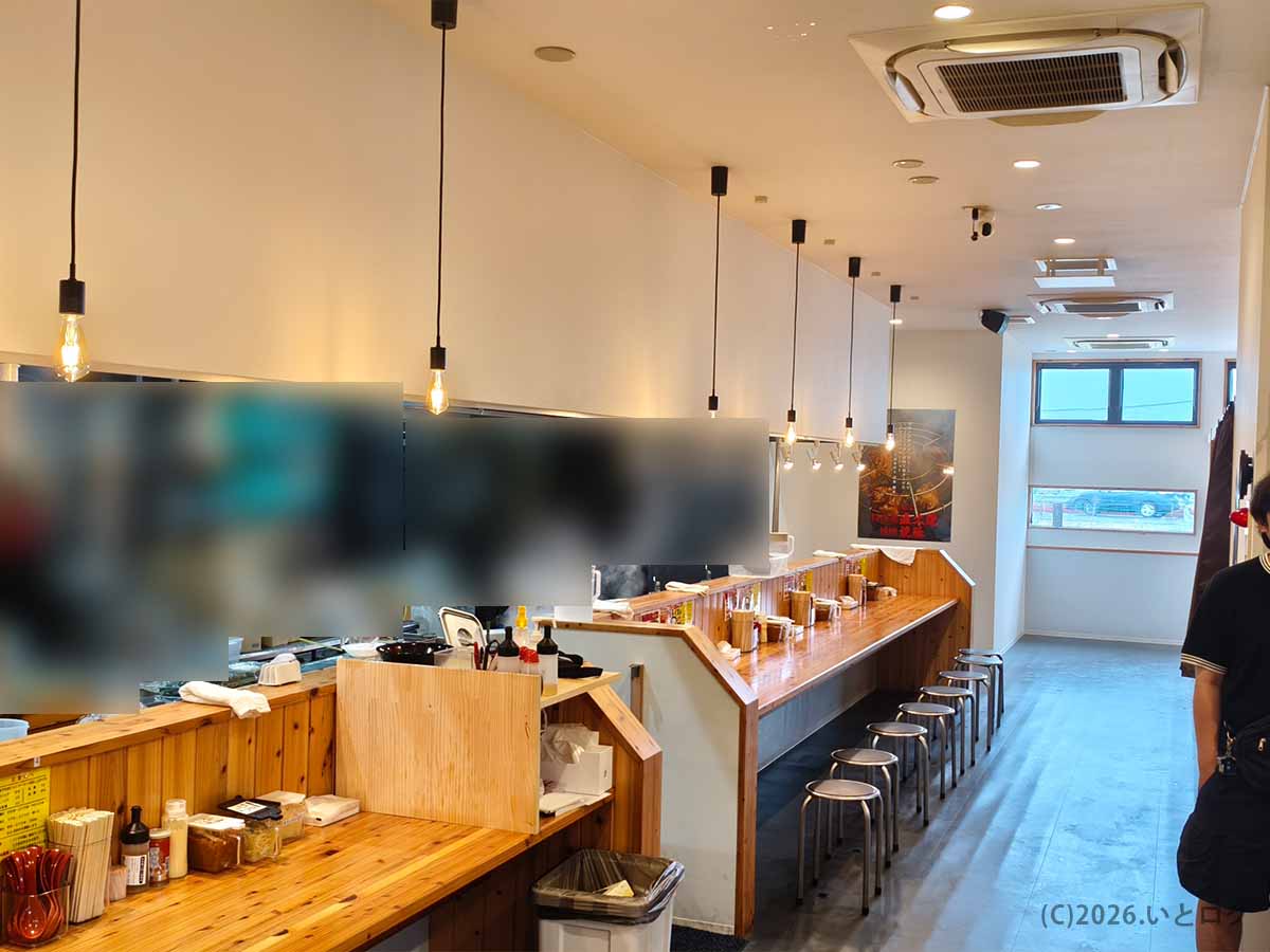 富山市の家系ラーメン店「王道乃印 富山家」の店内。木目調のカウンター席が奥まで続き、明るく清潔感のある空間になっている。