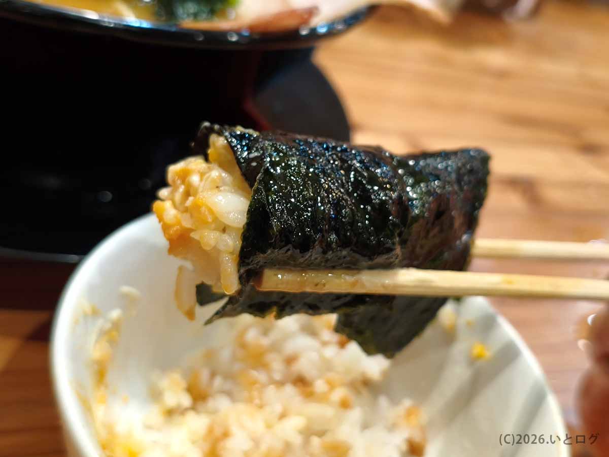 富山家のスープをまとった海苔でライスを巻いた一口。王道家系ラーメンならではの食べ方で、濃厚スープと白米の相性を楽しめる。