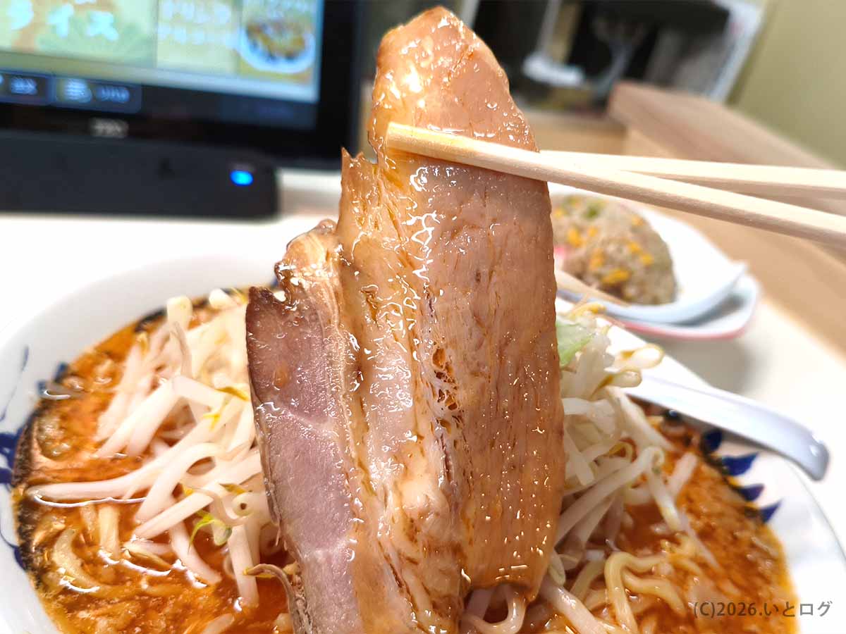 みやこいち 双葉店の辛みそタンメンにのる、脂身がついた大きなチャーシューを箸で持ち上げた様子