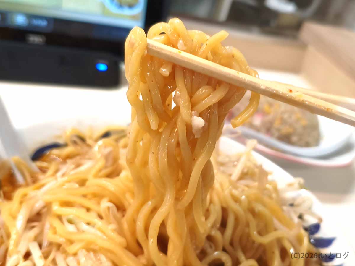 みやこいち 双葉店の辛みそタンメンから、スープをまとった中太の縮れ麺を箸で持ち上げた様子
