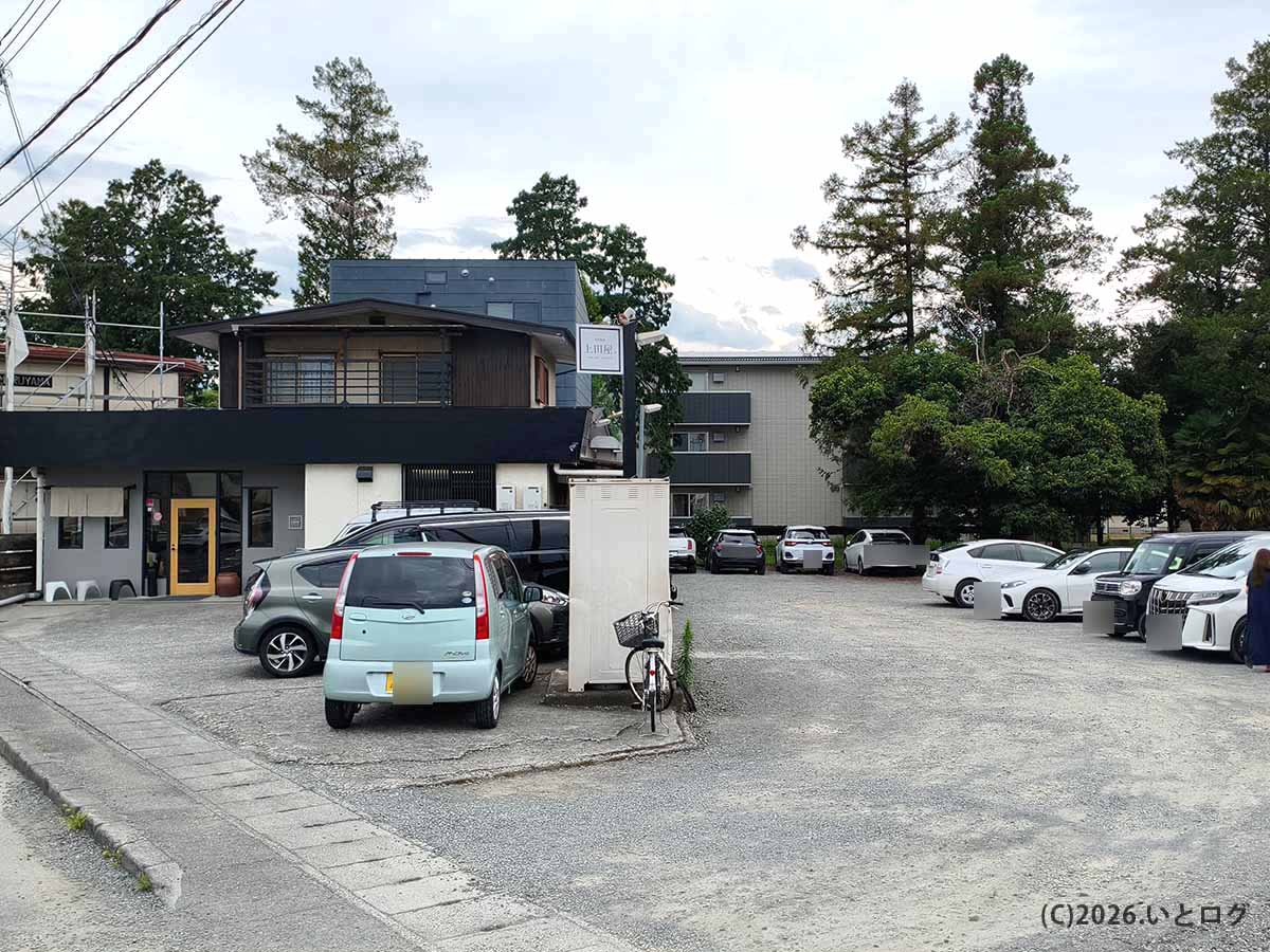 山梨県甲府市下飯田にあるラーメン店「上田屋」の店舗外観と、店前に広がる駐車場
