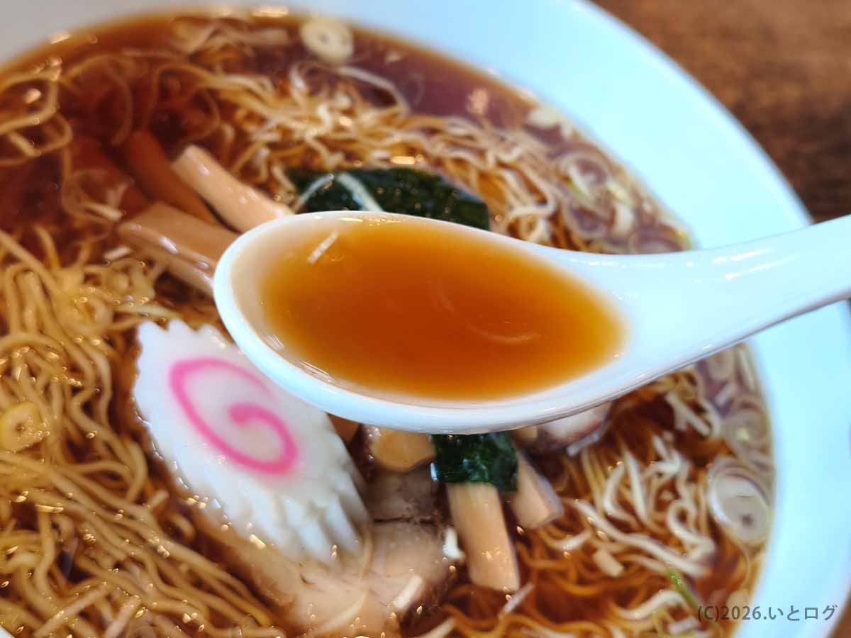 甲府市の上田屋で味わった、透き通った褐色の醤油ラーメンスープをレンゲですくった様子