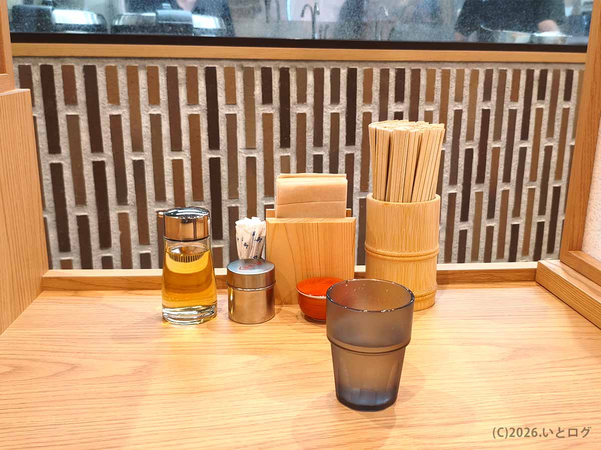 初志貫徹 甲斐竜王店のカウンターに並ぶ酢や香辛料、箸、爪楊枝などの卓上セット