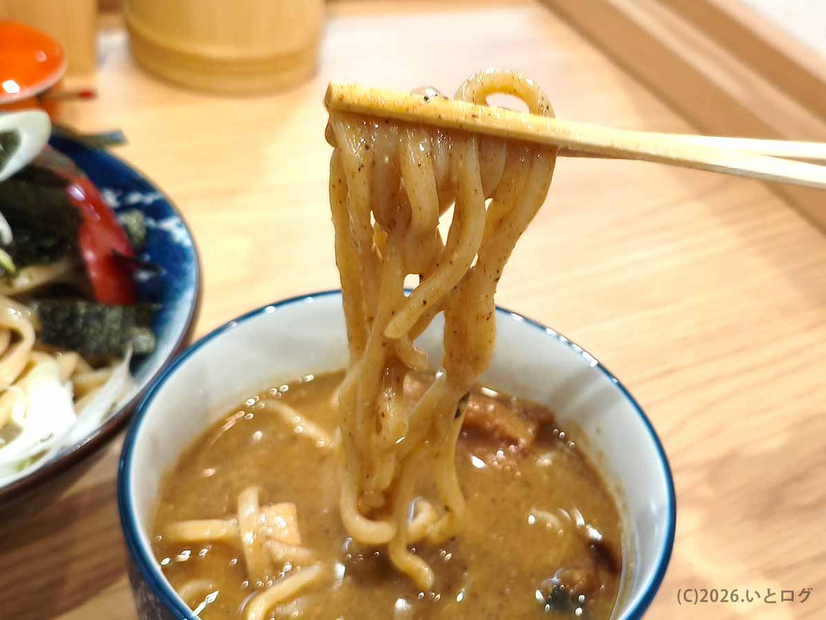 初志貫徹 甲斐竜王店の特上みそつけで、濃厚な味噌のつけ汁をまとった太麺を箸で持ち上げた様子