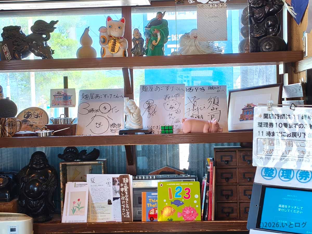 麺屋あごすけ店内の整理券受付付近とサイン・置物が並ぶ様子