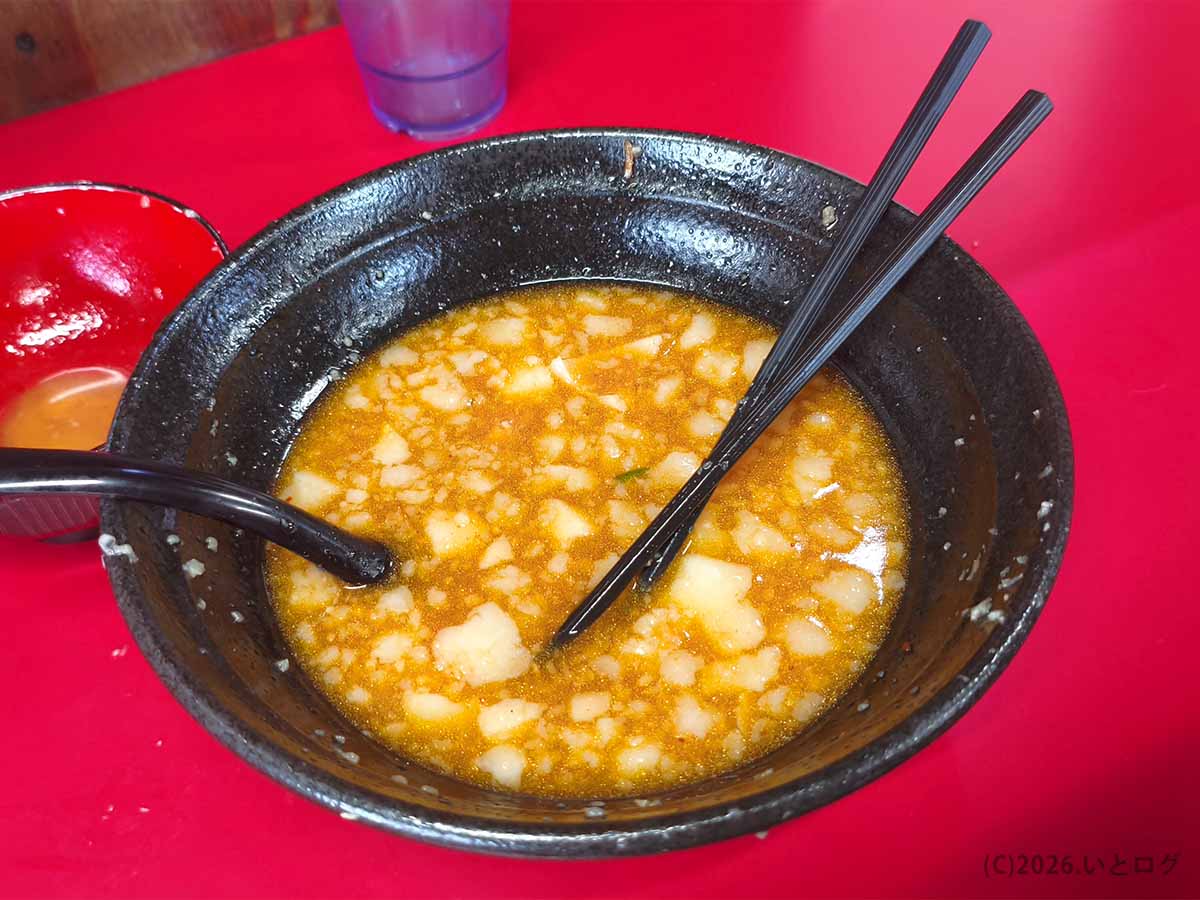 ラーメン二郎 新潟店の食後の丼。麺と具材を食べ終え、刻んだ背脂が浮かぶオレンジ色のスープが残っている。
