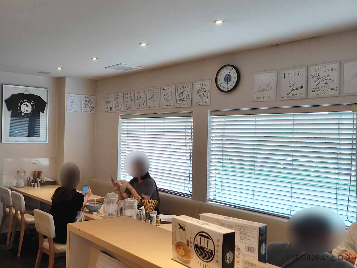 北海道千歳市のラーメン店IOrI(いおり)の店内。明るい木目調のカウンター席と壁に並ぶ著名人のサイン色紙。