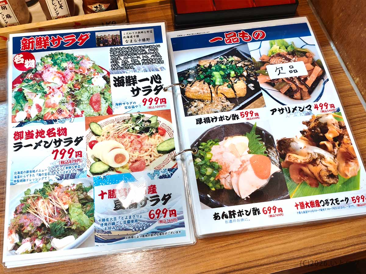 帯広の居酒屋「魚の一心」のメニュー表。海鮮一心サラダ、ラーメンサラダ、十勝産野菜のサラダ、厚揚げポン酢などが並ぶ。
