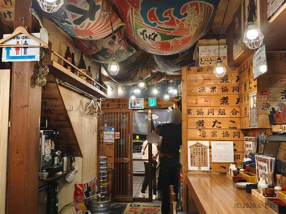 北海道帯広市の居酒屋「魚の一心」の店内。漁業協同組合の木箱や大漁旗、漁船を思わせる装飾が施されたカウンター席と入口付近。