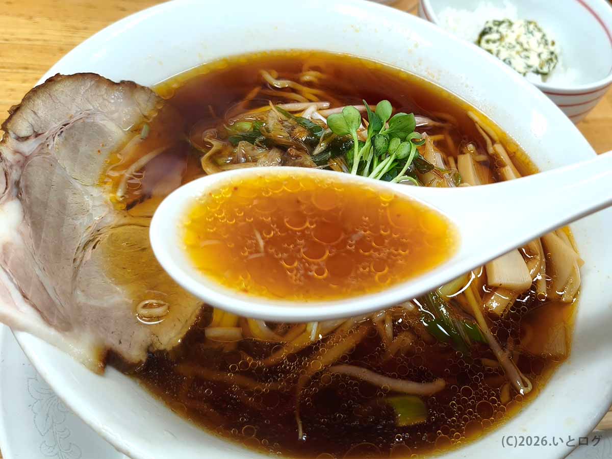 帯広のらーめんみすゞで提供されるラーメンの醤油色のスープ。レンゲには黄金色の油滴が浮かび、丼にはチャーシューや野菜が盛られている