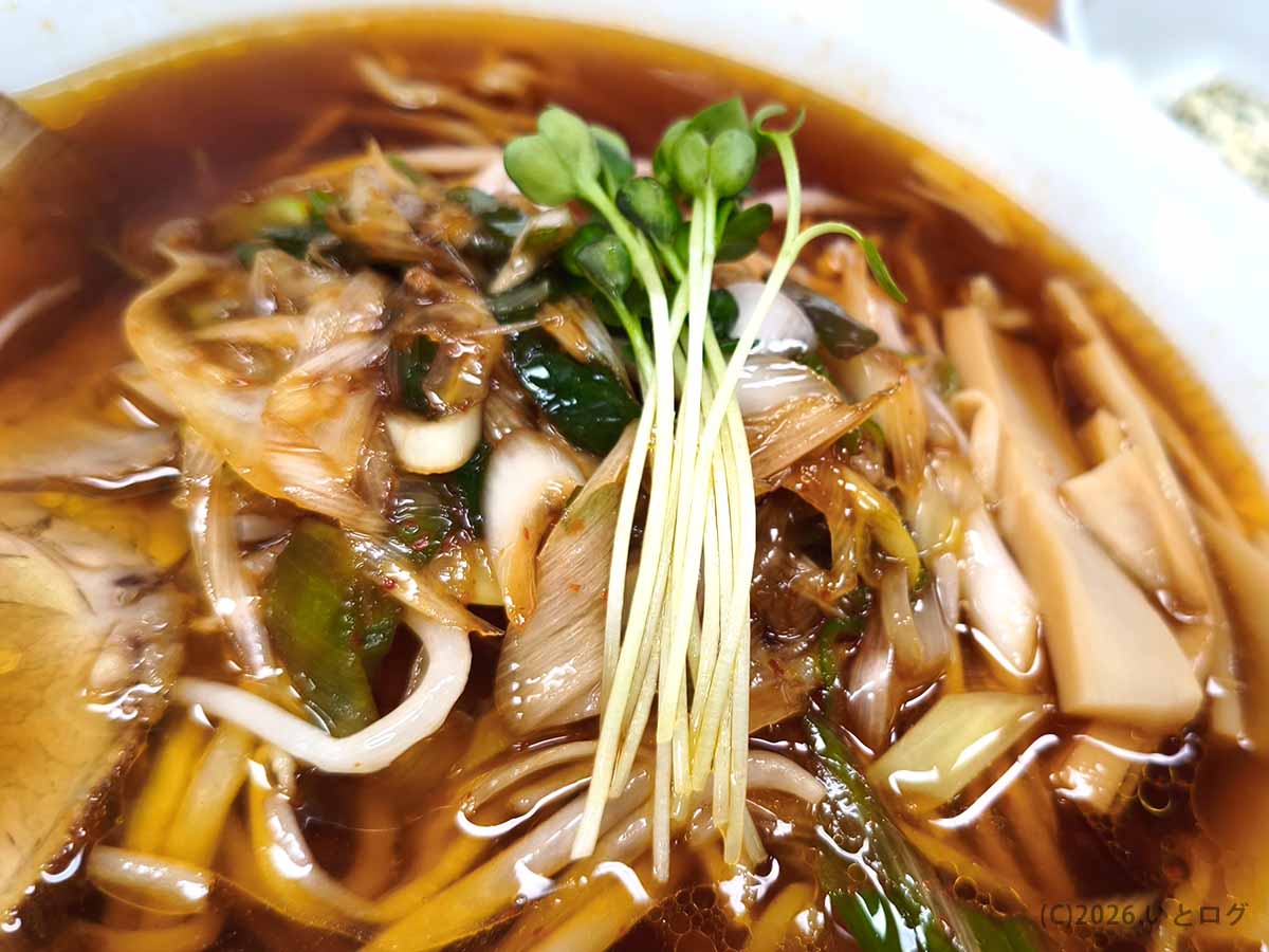 らーめんみすゞのラーメンに盛られたもやしやネギなどの野菜炒め。中央にカイワレがのり、周囲にはメンマと醤油色のスープが見える