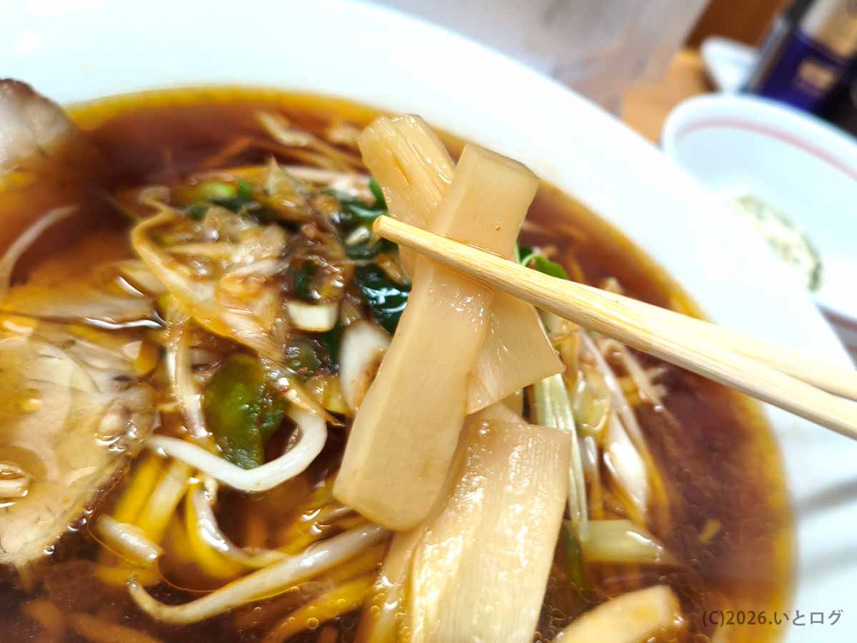 北海道帯広市のラーメンみすゞで食べたラーメンのメンマ。箸で持ち上げた太めのメンマに醤油色のスープが絡んでいる