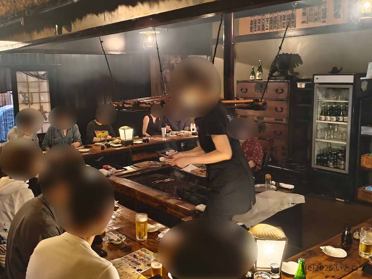 北海道釧路市の老舗「炉ばた」の店内。中央の炭火焼き場を囲む木製カウンターに客が座り、スタッフが料理を提供している様子