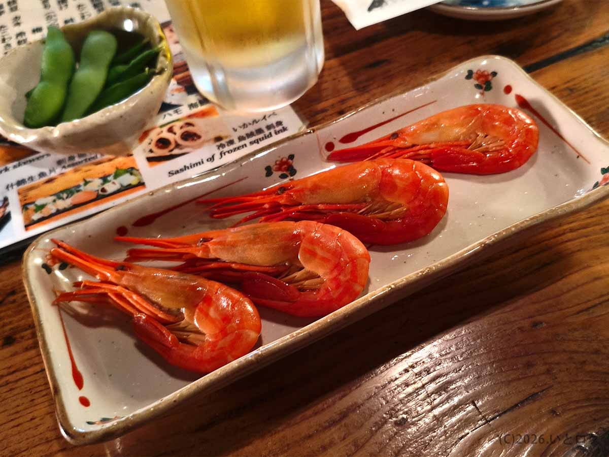 北海道釧路市の炉ばたで提供されたエビ料理。細長い長方形の皿に、赤く色づいた殻付きのエビが4尾並んでいる