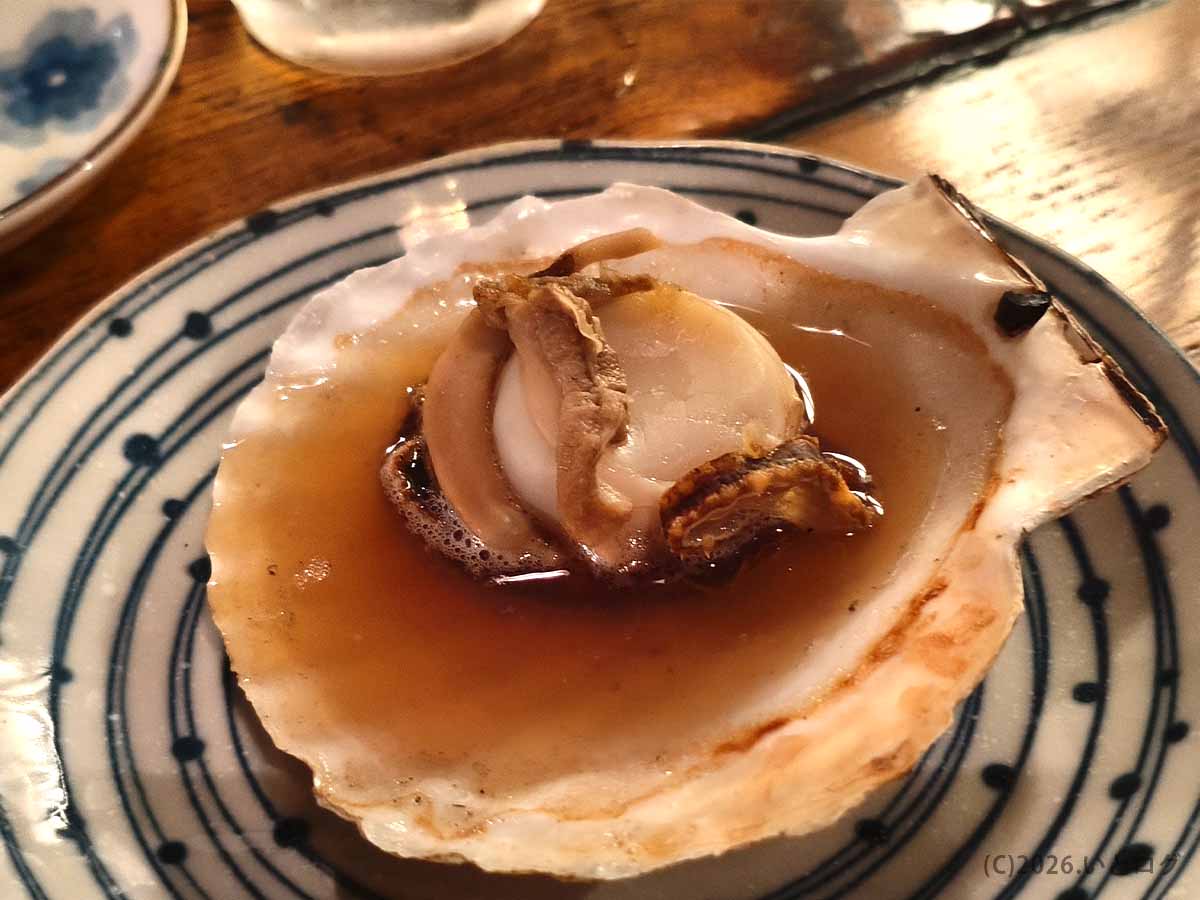 北海道釧路市の炉ばたで提供されたホタテの貝焼き。大きな貝殻にホタテの身が盛られ、褐色の汁がたまっている