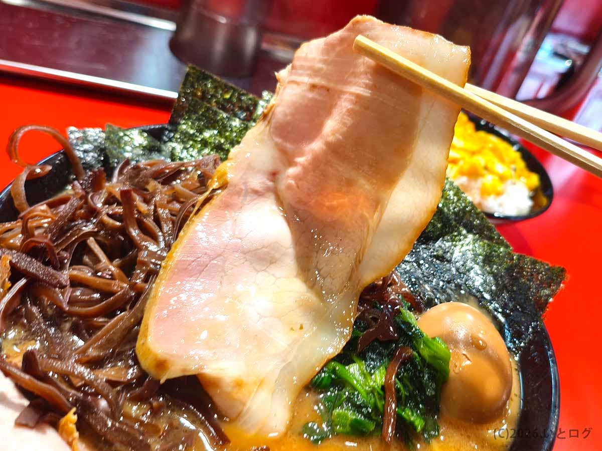 秀道家のラーメンにのった大判のチャーシューを箸で持ち上げた様子