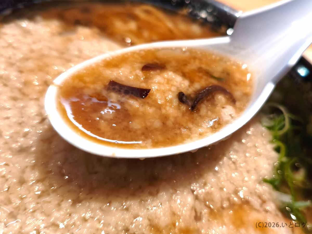 あなたの心を鷲掴みの豚骨スープに浮かぶ大量の背脂とキクラゲをレンゲですくった様子