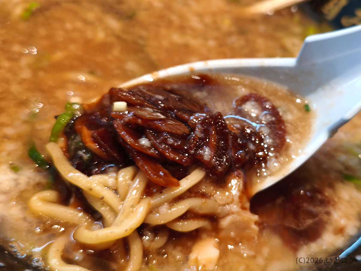 春日原のラーメン店「あなたの心を鷲掴み」でニンニク醤油と麺を濃厚豚骨スープと一緒にすくった様子