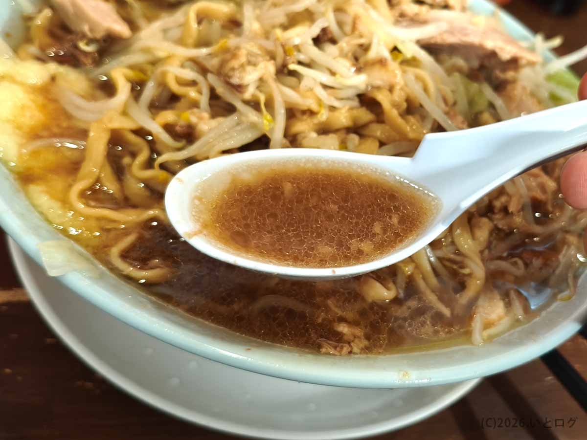 龍麺ふえ郎のラーメンのスープ。表面に油が浮かぶ茶褐色のスープをレンゲですくった様子