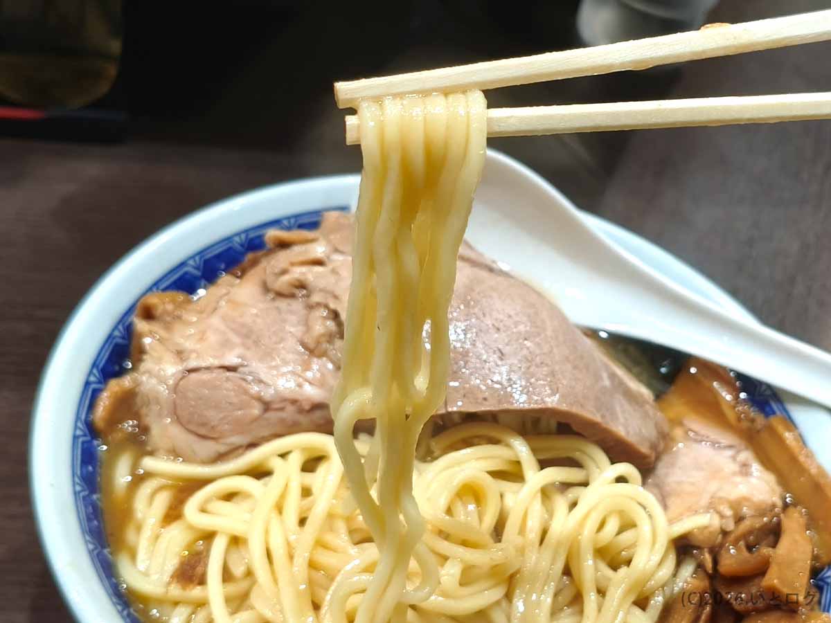 べんてん成増のラーメンに使用された中太麺を箸で持ち上げた様子。つやのあるストレート麺とたっぷり盛られたチャーシュー