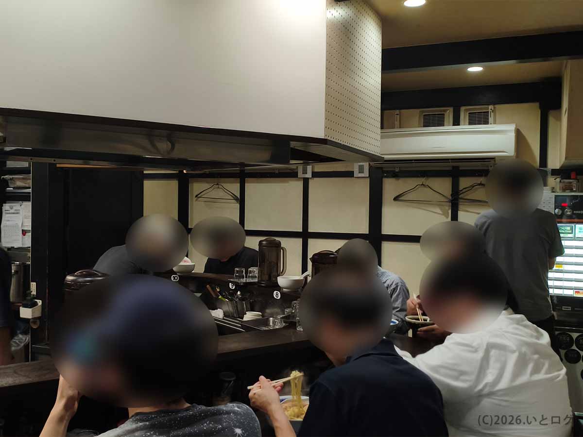 東京都練馬区の中華そば べんてんの店内風景。カウンター席でラーメンを食べる客と厨房、券売機が見える様子