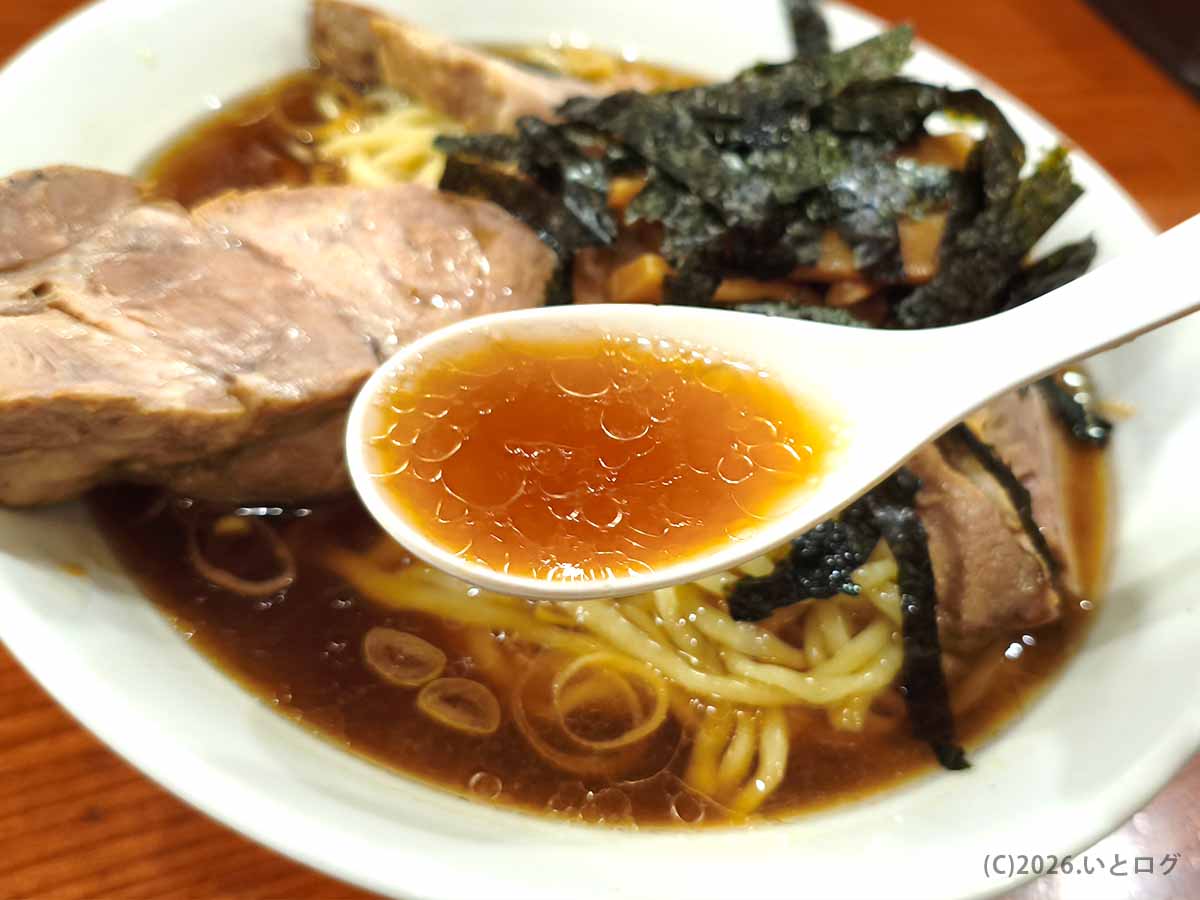 新宿のらあめん満来で食べたチャーシューらあめんの醤油スープ。表面に油が浮かび、レンゲにすくった様子