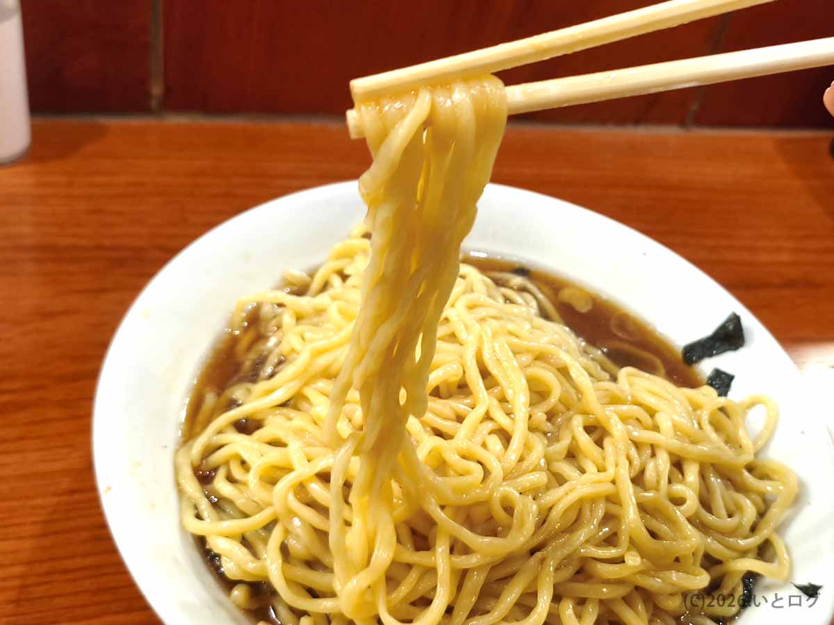 新宿のらあめん満来のチャーシューらあめん。もちもちとした太めの麺を箸で持ち上げた様子