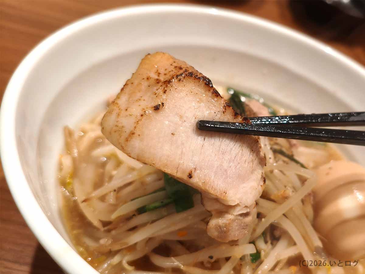 甲府の町中華ダイニング蒔季彩の味噌ラーメンにのる厚切りチャーシューを箸で持ち上げた様子