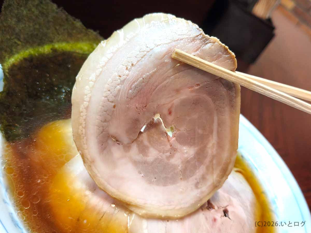 甲府市「麺どころ 千石」のラーメンにのる大判チャーシューを箸で持ち上げた様子