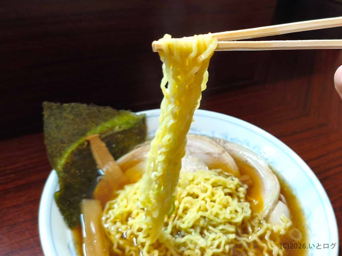 甲府市「麺どころ 千石」の醤油ラーメンから黄色い縮れ麺を箸で持ち上げた様子