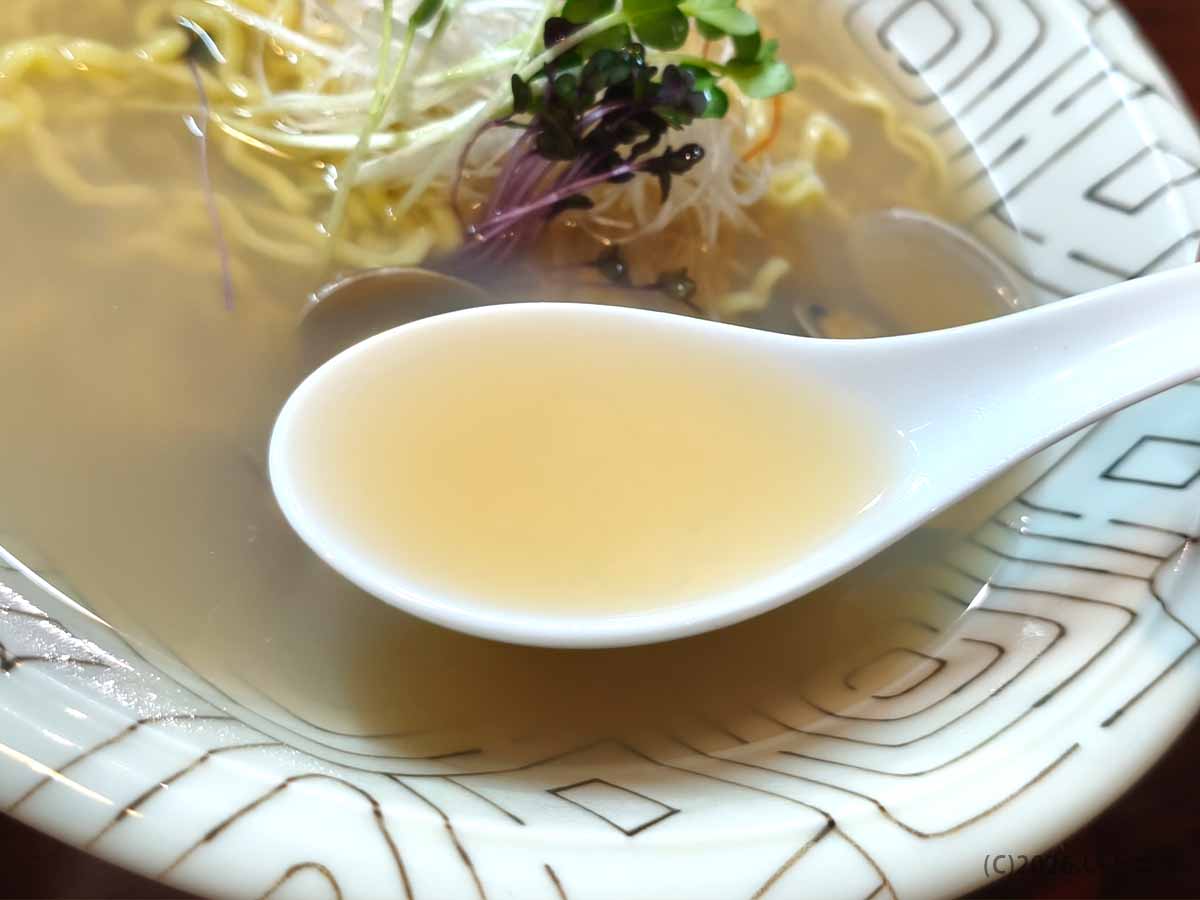 甲府市「麺どころ 千石」の貝だし塩ラーメンの透明感ある塩スープをレンゲですくった様子
