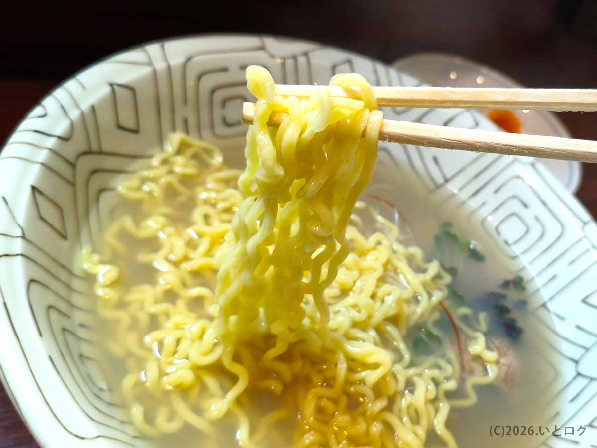 甲府市「麺どころ 千石」の貝だし塩ラーメンから縮れ麺を箸で持ち上げた様子