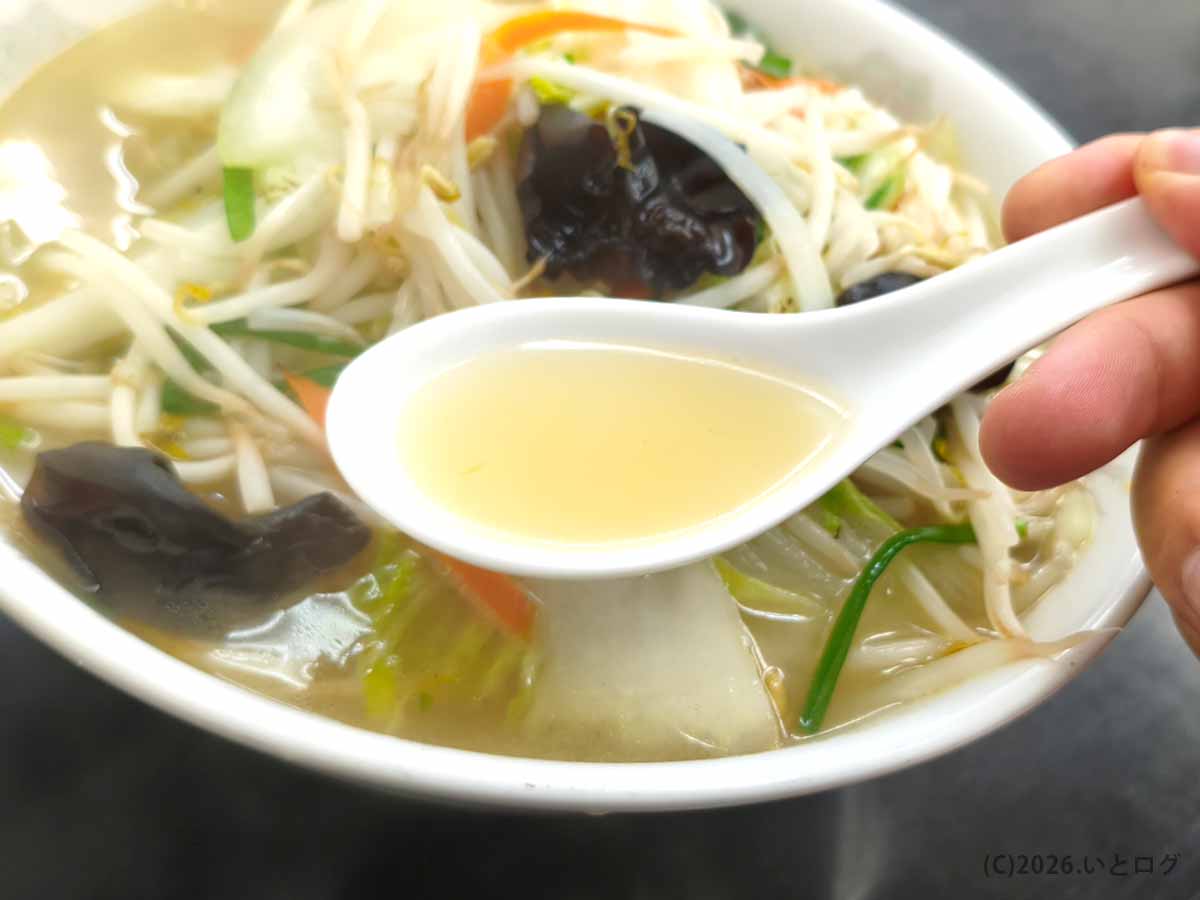 甲府の中華 福吉で人気のタンメン。白いレンゲですくった淡い黄金色のスープと、丼いっぱいに盛られた野菜