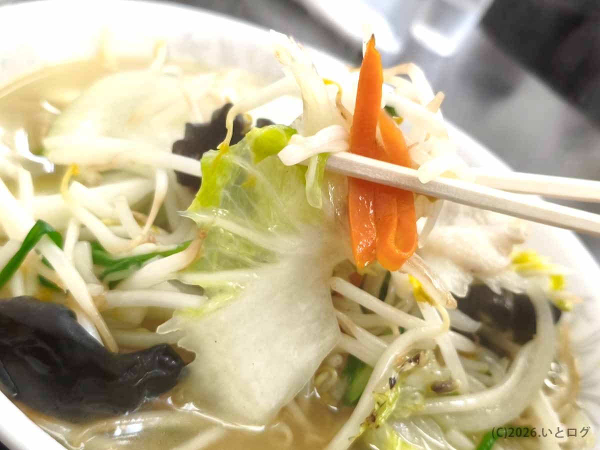 中華 福吉のタンメンに入った白菜、もやし、ニンジンなどの野菜を箸で持ち上げた写真。具材の豊富さが伝わるアップ