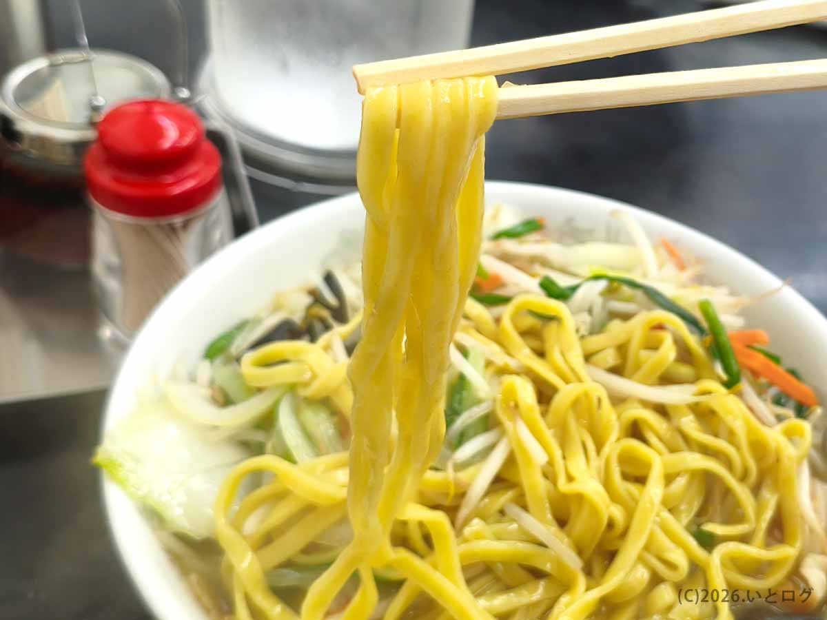 山梨県甲府市の中華 福吉のタンメン。箸で持ち上げた黄色い平打ち麺と、丼にたっぷり盛られたもやしやニラ