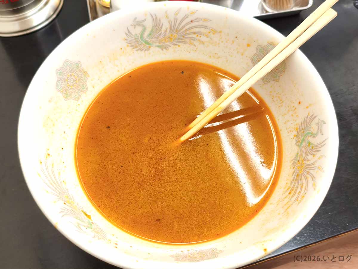 甲府市の中華 福吉でタンメンを食べ進めた後の丼。麺や野菜がなくなり、赤みを帯びたスープが残っている様子