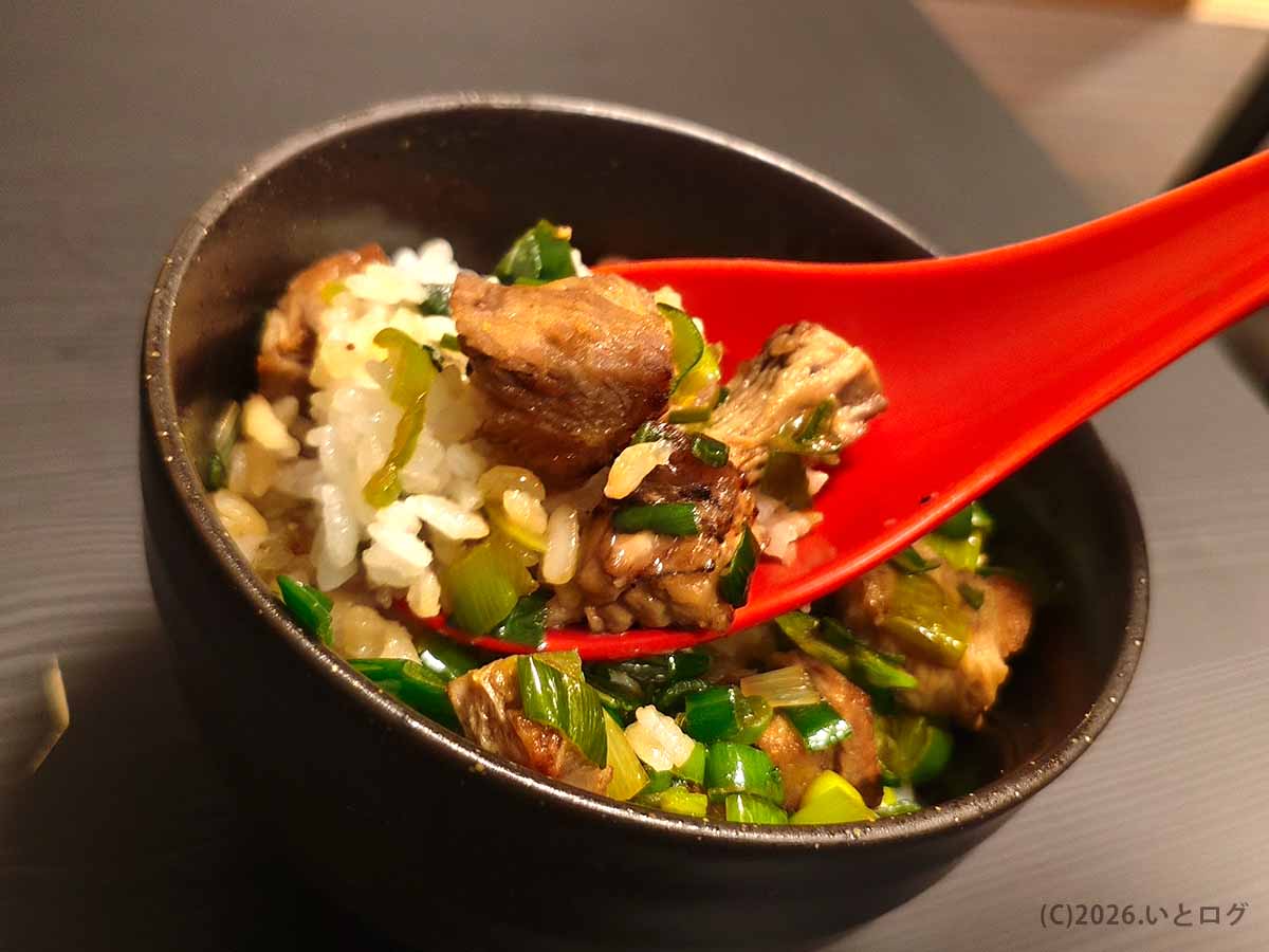 甲府市の油そば専門店あぶらギルドのチャーシュー丼をレンゲですくった様子。タレの染みた角切りチャーシューと青ネギ、白米が一緒に味わえる。