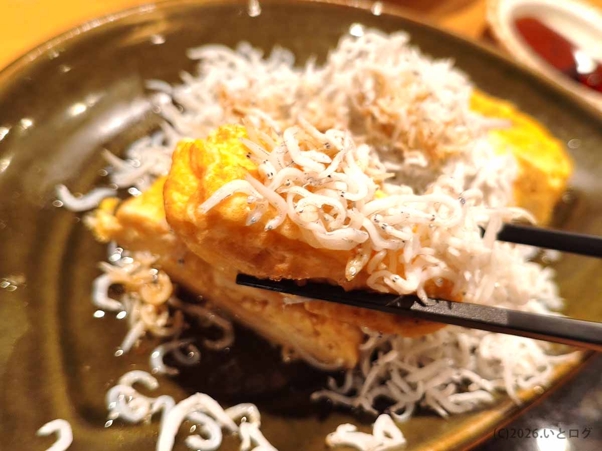 二代目たわらのしらすのだし巻き卵。箸で持ち上げた厚い卵焼きの上に小さなしらすがたっぷり載っている