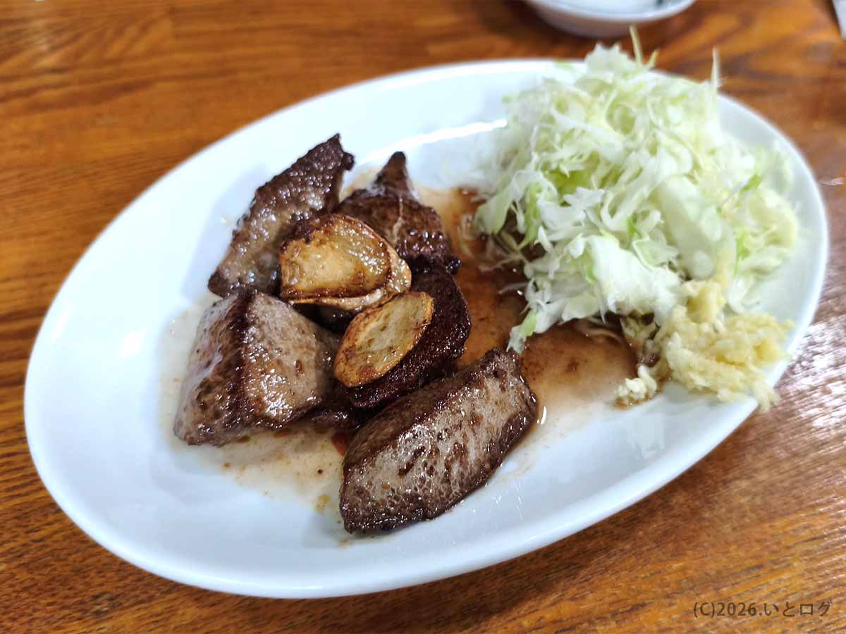 ニンニクと千切りキャベツが添えられたどてやき下條のレバー塩焼