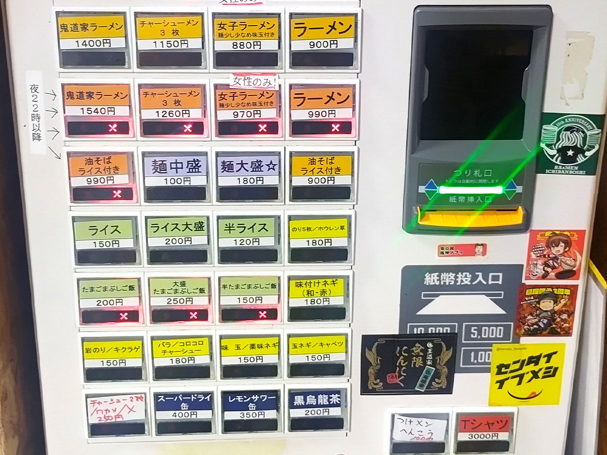 鬼道家の券売機。基本のラーメンから女子ラーメン、油そば、ライスや学割対象メニューまでずらりと並ぶ。深夜22時以降は一部メニュー変更あり。