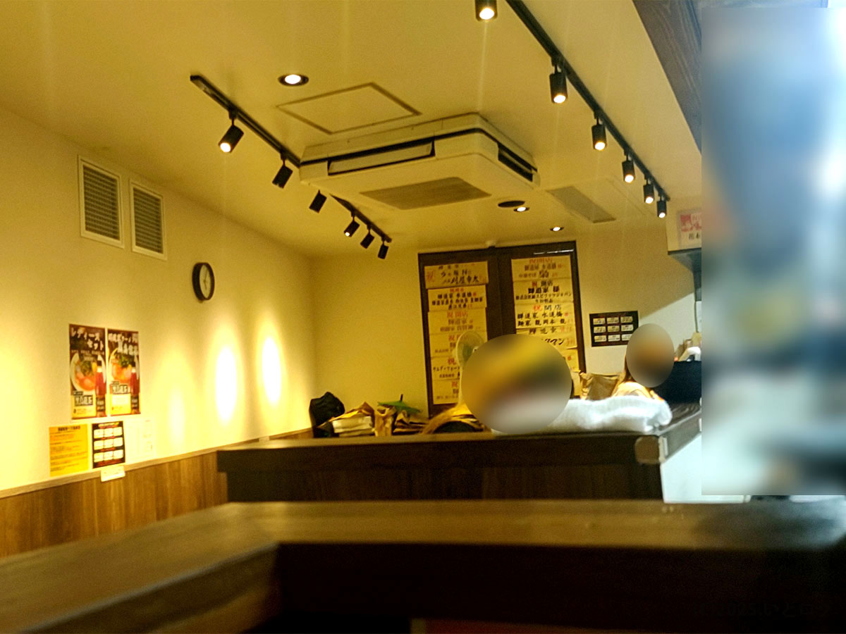 輝道家 水道橋店の店内の様子。壁にメニューが掲示され、カウンター席とテーブル席が並ぶ落ち着いた空間。水道橋の家系ラーメン店としてアクセスもしやすい。